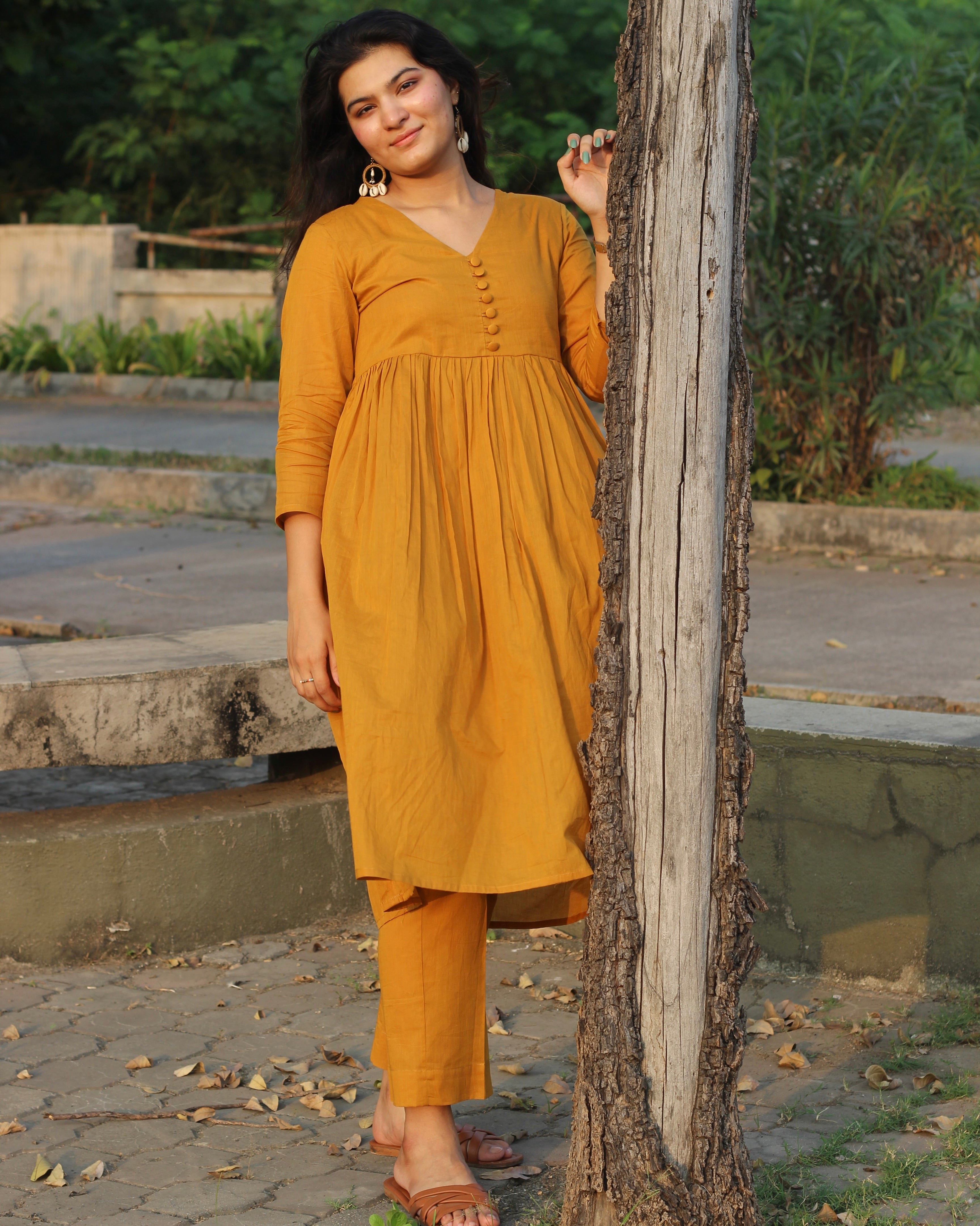 Mustard mul cotton kurta pant set with V-neck, cloth-covered buttons, pleated pattern from yoke, 3/4 sleeves, and pockets, in our best-selling design