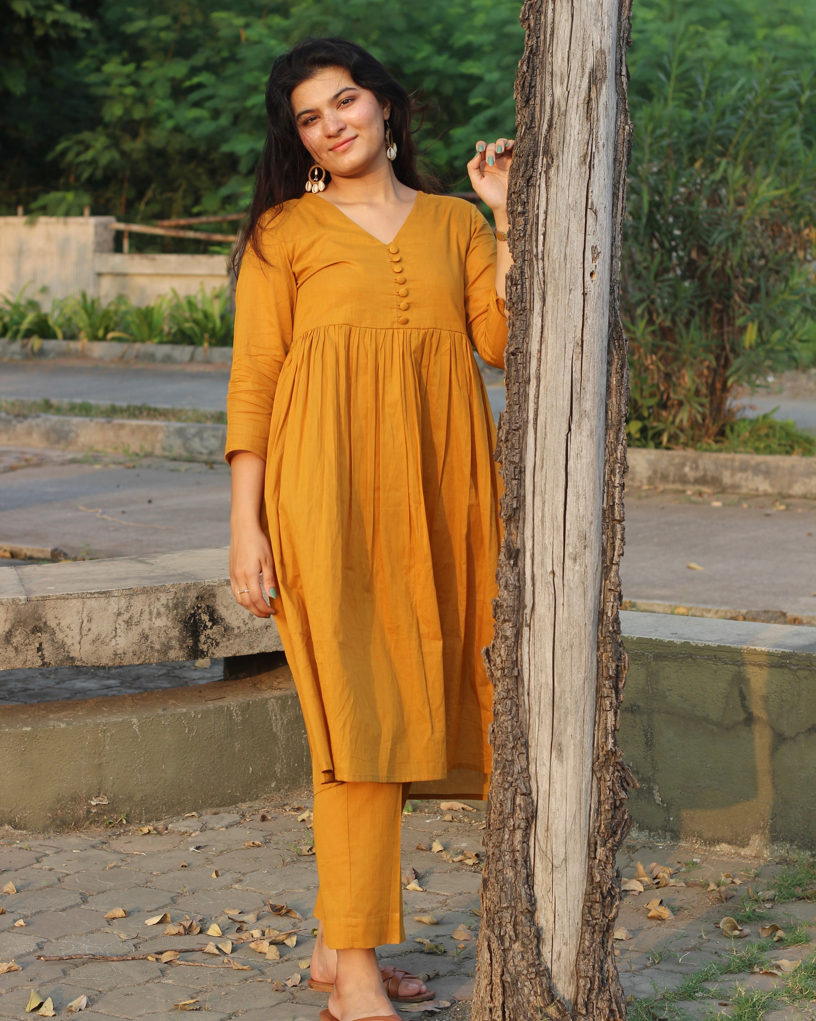 Mustard mul cotton kurta pant set with V-neck, cloth-covered buttons, pleated pattern from yoke, 3/4 sleeves, and pockets, in our best-selling design
