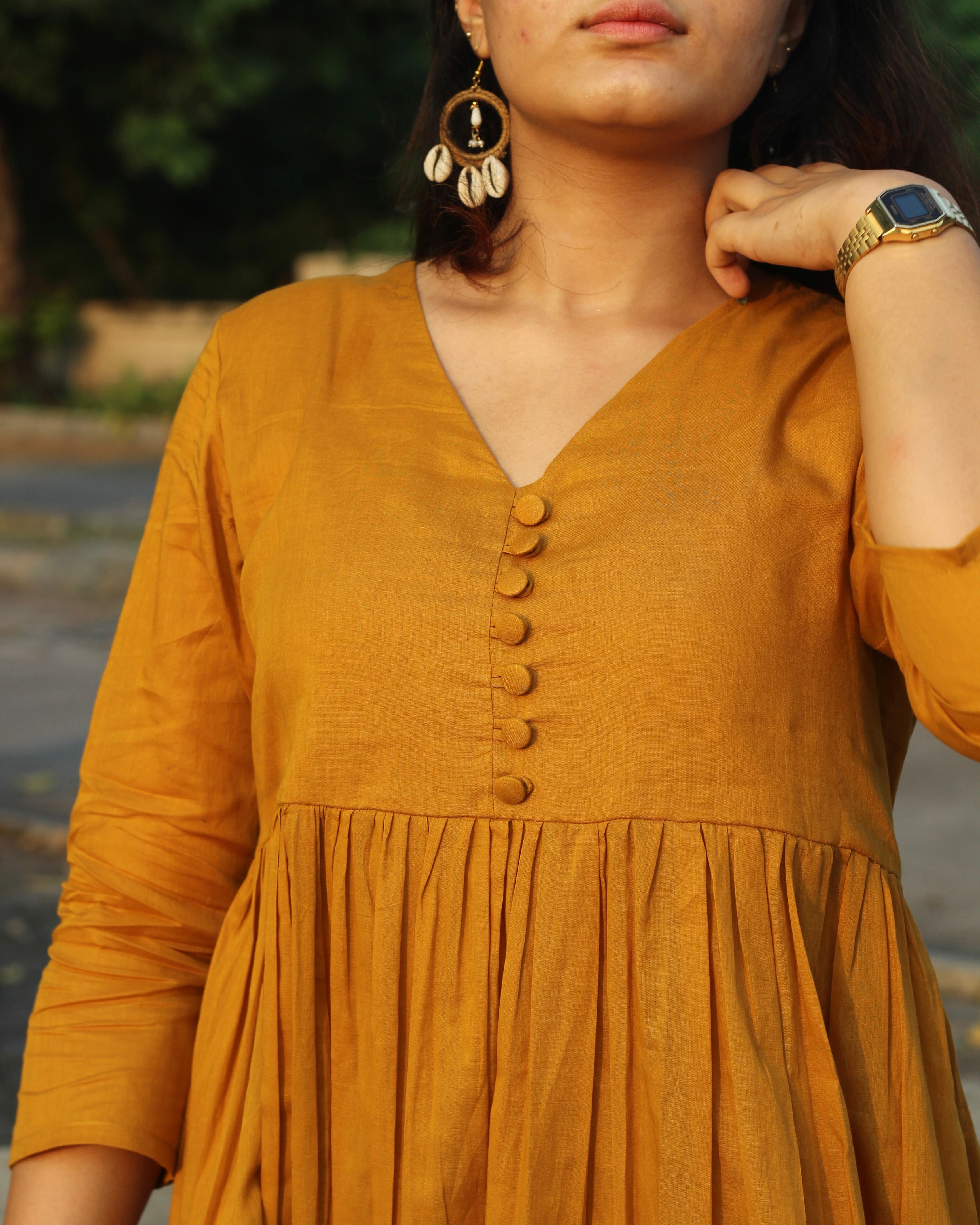 Mustard mul cotton kurta pant set with V-neck, cloth-covered buttons, pleated pattern from yoke, 3/4 sleeves, and pockets, in our best-selling design