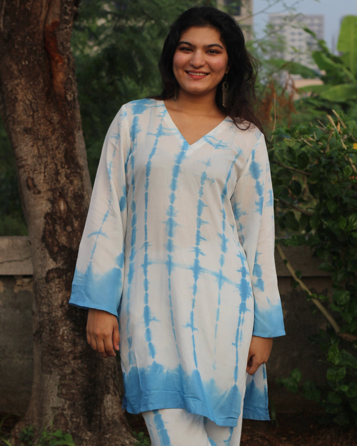 Shibori print muslin co-ord set featuring a knee-length straight kurta with V-neck and bell sleeves, paired with lined pants, in a white and blue palette