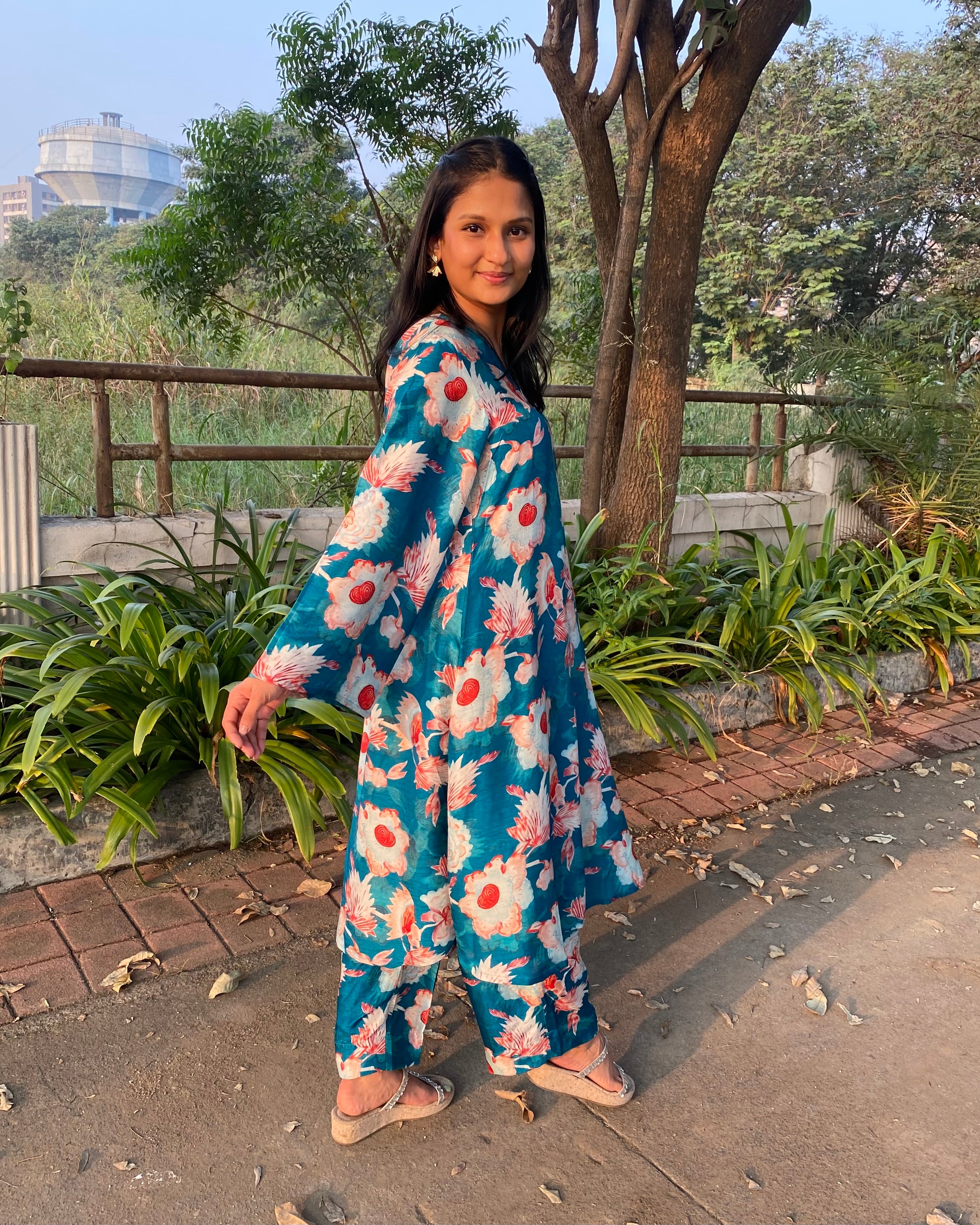 Bright teal floral silk kurta set with big white and red florals, unique V-neck with box pattern, and full bell sleeves for a chic summer look