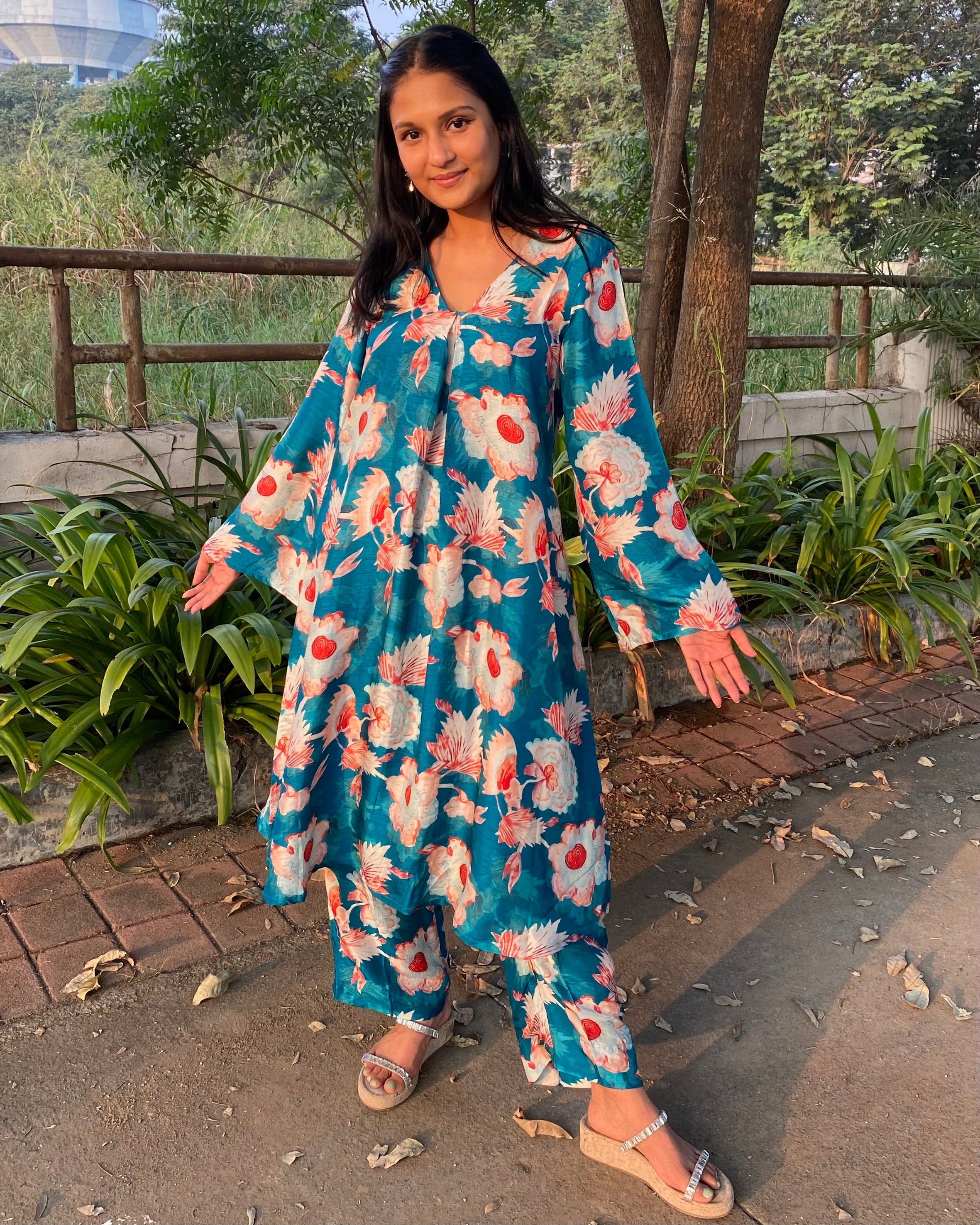 Bright teal floral silk kurta set with big white and red florals, unique V-neck with box pattern, and full bell sleeves for a chic summer look