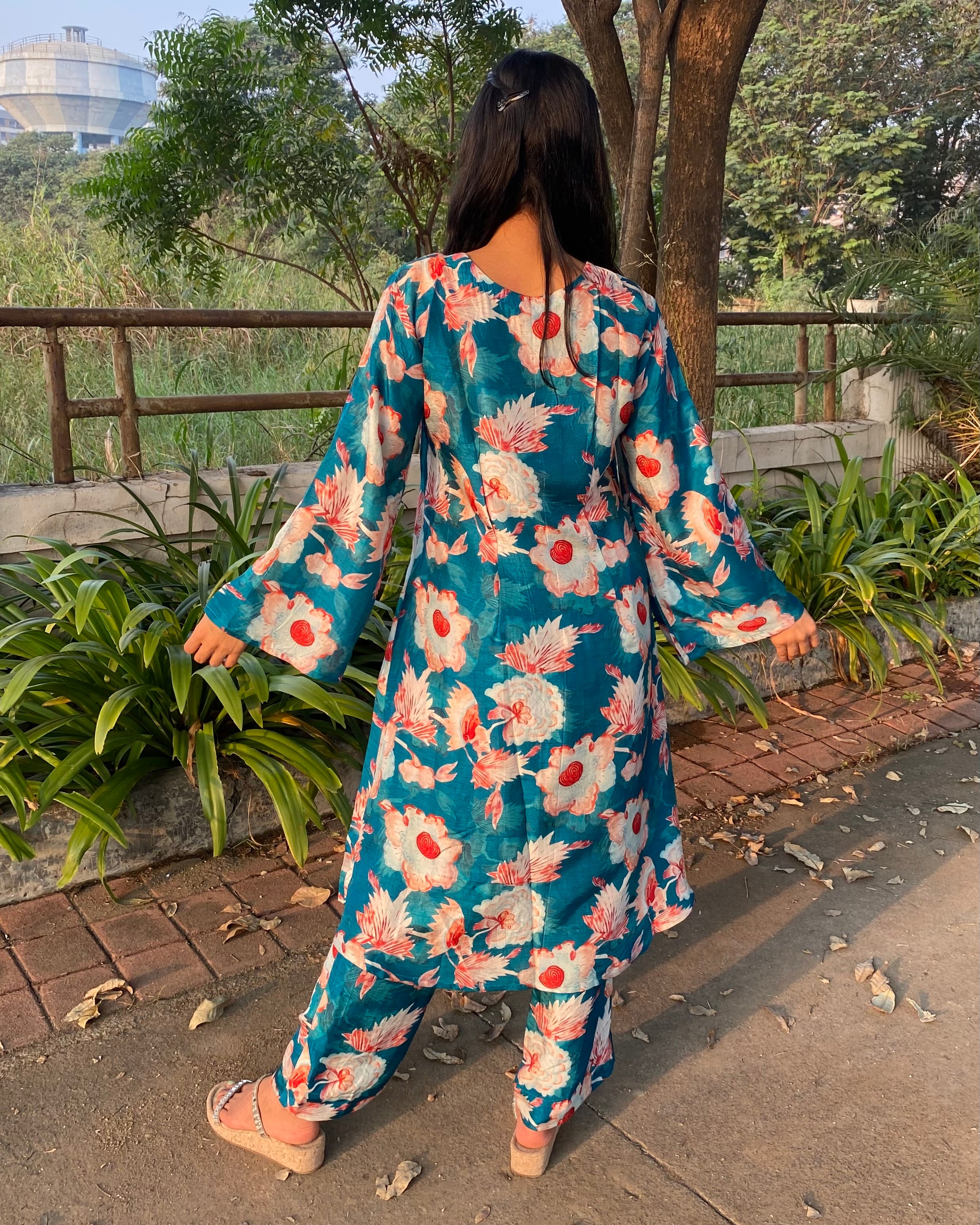 Bright teal floral silk kurta set with big white and red florals, unique V-neck with box pattern, and full bell sleeves for a chic summer look