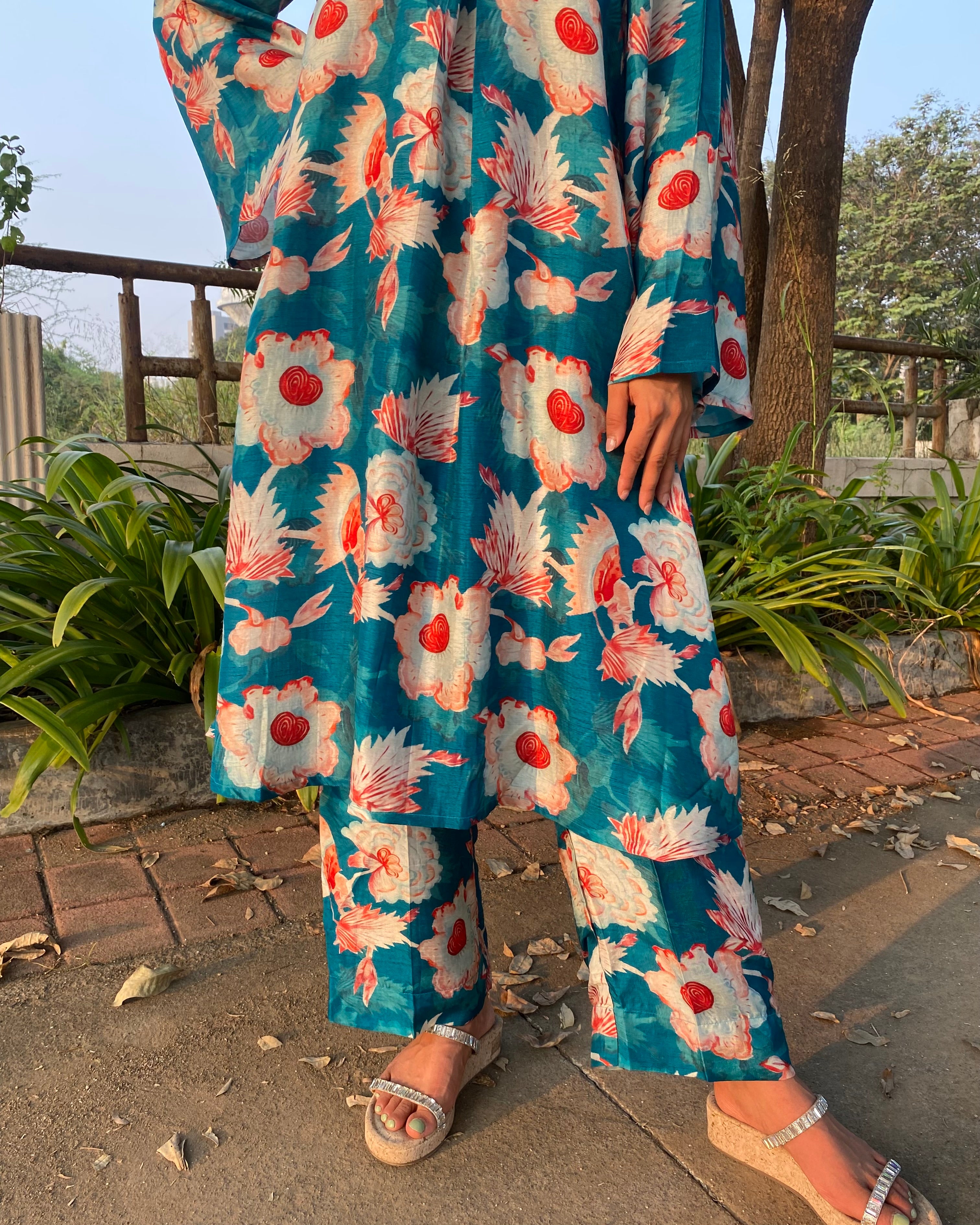 Bright teal floral silk kurta set with big white and red florals, unique V-neck with box pattern, and full bell sleeves for a chic summer look