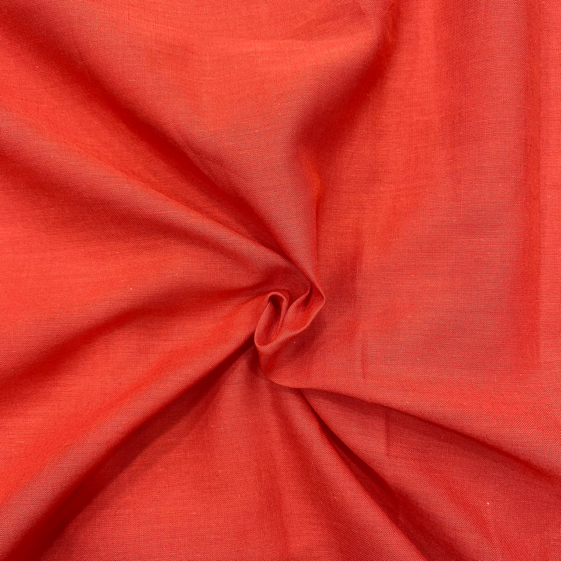 Rust orange mul cotton fabric close-up, showcasing the vibrant color and delicate texture